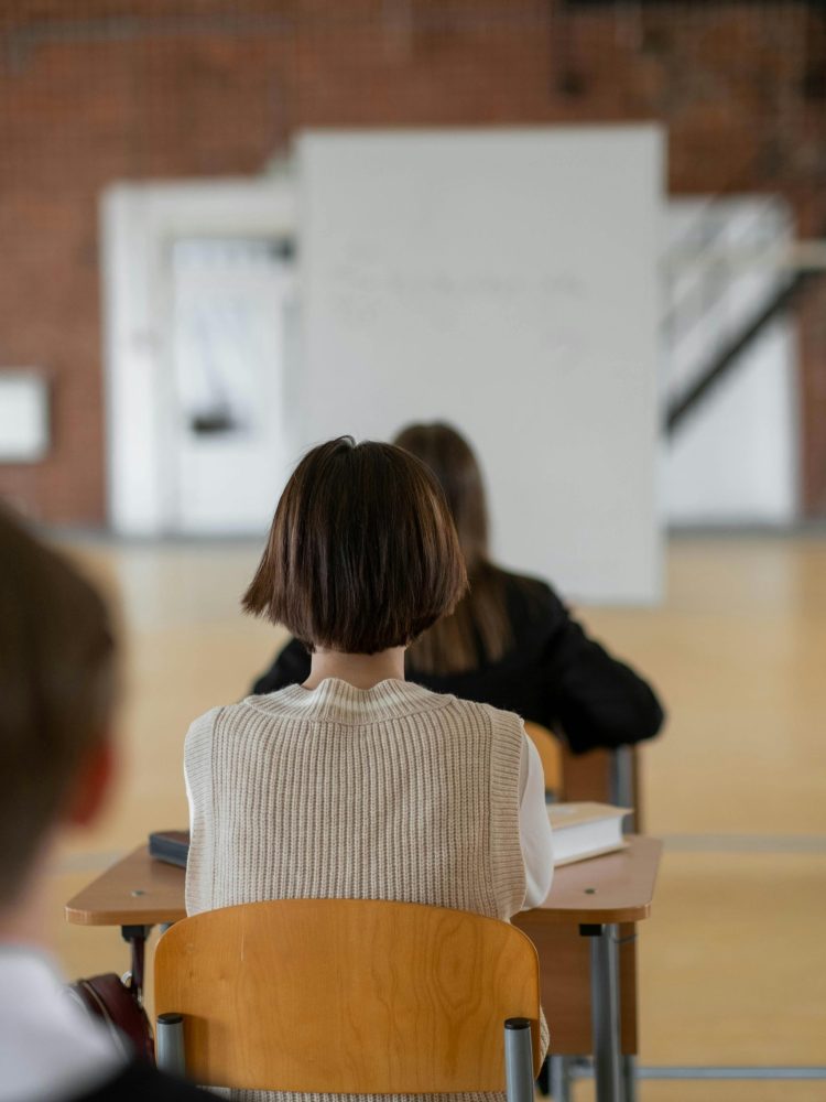 Focused students seated in class, attentively looking towards the whiteboard.