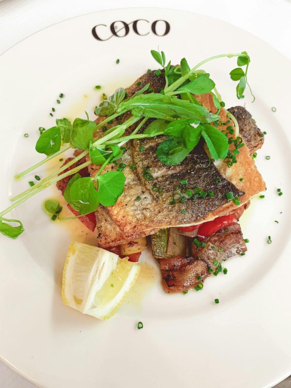 Delicious gourmet fish dish served with fresh greens and lemon for a delightful meal.